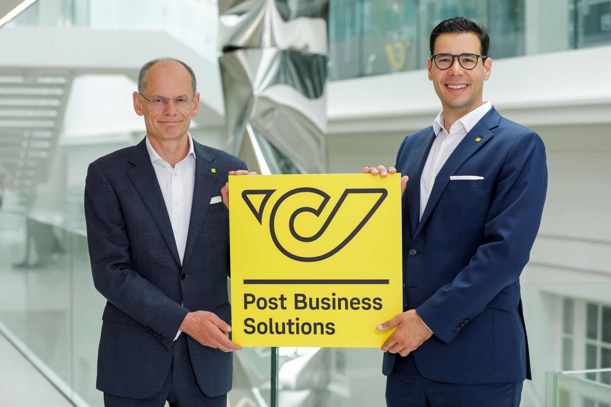 DI Walter Oblin, Generaldirektor-Stellvertreter und Vorstand für Brief & Finanzen, Mag. George Wallner, M.Sc., Geschäftsfeldleiter Post Business Solutions, beide Österreichische Post AG, halten ein Schild mit der Aufschrift: Post Business Solutions